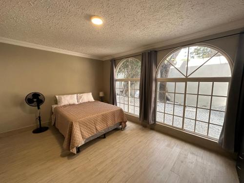 a bedroom with a bed and two large windows at Villa Sicilia in Guatemala