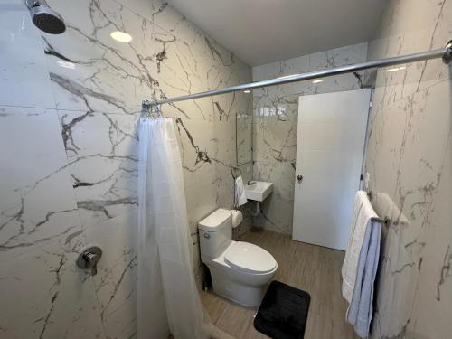a white bathroom with a toilet and a shower at Villa Sicilia in Guatemala