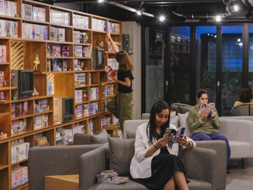 a woman sitting in a library using her cell phone at Giappo Franca Kyoto in Kyoto