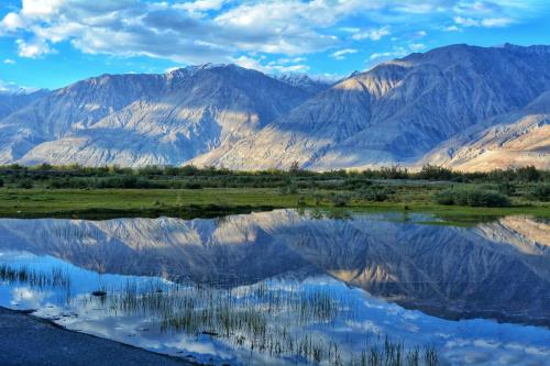 a reflection of mountains in a body of water at The Grand Lodge Pangong in Lukung