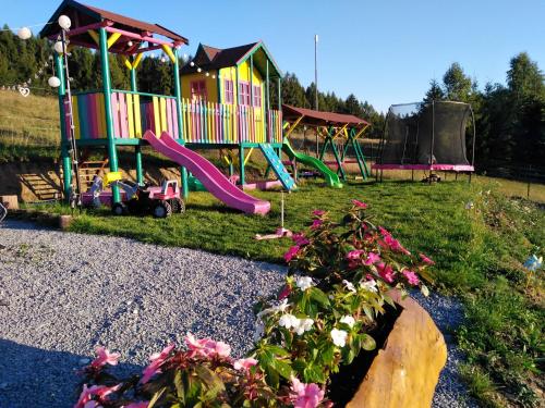 a playground with a slide in a yard with flowers at Cabana Deasupra Norilor in Gheorgheni