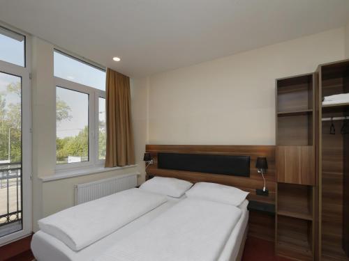 B&B HOTEL Berlin-Adlershof في برلين: غرفة نوم بسرير ابيض كبير ونافذة