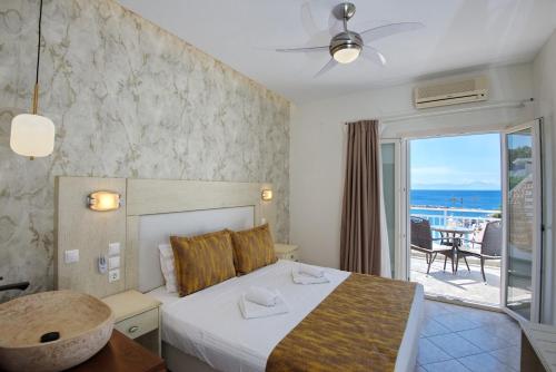 a bedroom with a bed and a balcony with the ocean at Pension Votsi in Votsi