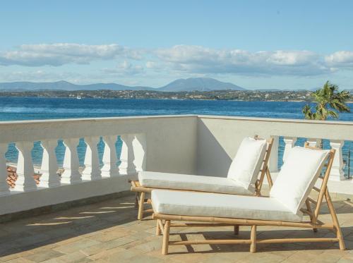 dwa krzesła siedzące na balkonie z widokiem na ocean w obiekcie Teresa Spetses w mieście Spetses