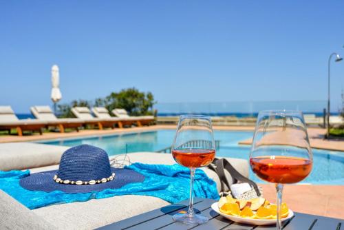 dois copos de vinho numa mesa ao lado de uma piscina em Panthea Luxury Living em Kolymvari