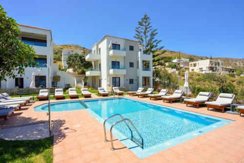 a swimming pool with lounge chairs and a building at Panthea Luxury Living in Kolymvari