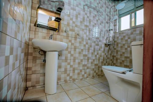 een badkamer met een wastafel en een toilet en een raam bij Kigali Wings Apartment 4 in Kigali