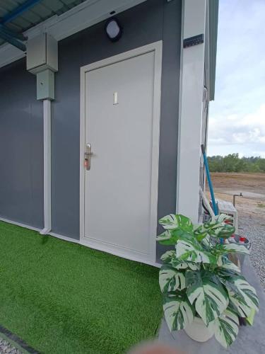 eine Tür an der Seite eines Hauses mit Gras in der Unterkunft Redang Bro Roomstay in Setiu