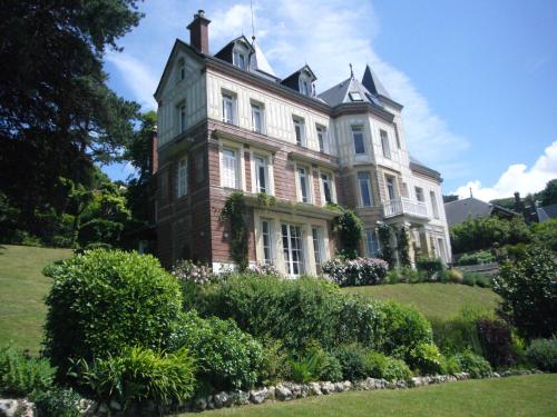 duży dom na szczycie wzgórza z krzakami w obiekcie Chambres d'Hôtes les Charmettes w Étretat