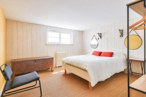 Un dormitorio con una cama y una silla dentro. en Maison pour 10 avec piscine chauffée, en La Barre-de-Monts