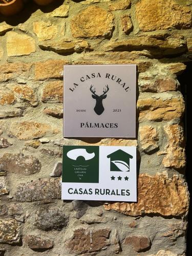 a sign on the side of a stone wall at La Casa Rural de Pálmaces in Pálmaces de Jadraque