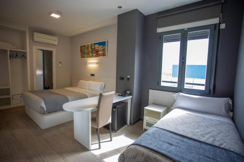 a hotel room with two beds and a table and a desk at Hotel LB Villa De Cuenca in Cuenca