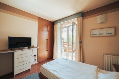 a bedroom with a bed and a tv and a window at Villa Dorottya in Balatonföldvár