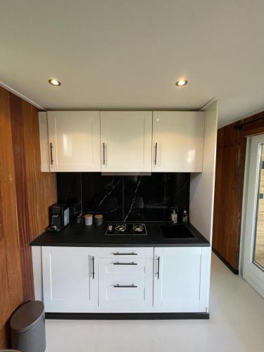 a kitchen with white cabinets and a black counter top at Ben's Cabine - De Hollandse Boerderij in Bodegraven