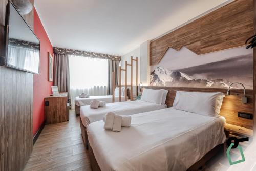 two beds in a hotel room with red walls at HOTIDAY Chalet Sestriere Vialattea in Sestriere