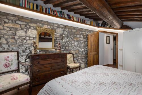 a bedroom with a stone wall with a bed and a mirror at La Petrosa in Radda in Chianti