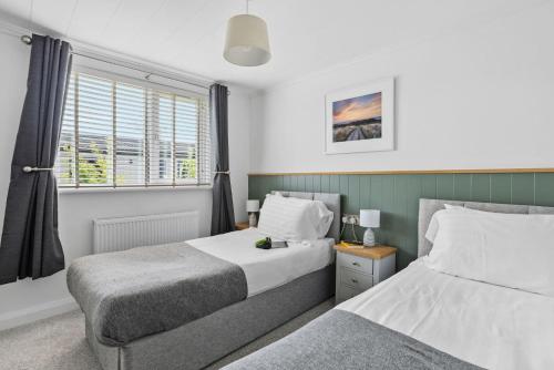 1 dormitorio con 2 camas y ventana en Snowdrop Lodge, 9 Roadford Lake Lodges, en Lifton