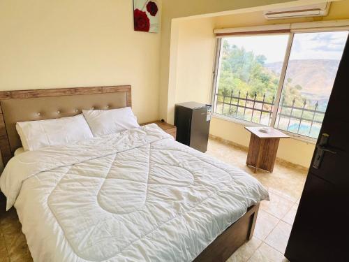 a bedroom with a large bed with a large window at منتجع وفندق جدارا Jadara Resort & Hotel in Um Qeis