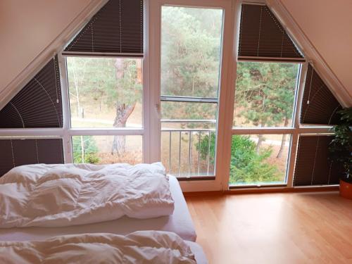 a bedroom with three large windows and a bed with white sheets at Die Blaue Lagune, Hinter Den Dünen in Prerow