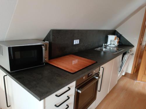 a kitchen with a black counter top with a microwave at Die Blaue Lagune, Hinter Den Dünen in Prerow