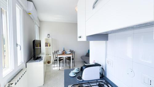 a white kitchen with a stove and a table at Alice by Ca-Sa Check in Chioggia