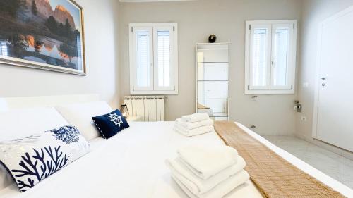 a white bedroom with a white bed and two windows at Alice by Ca-Sa Check in Chioggia