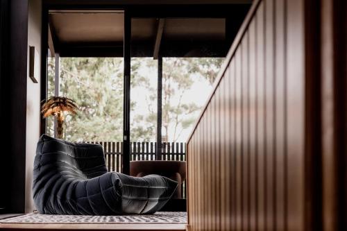 a black leather couch sitting in a room with a window at 'Sisters' - Cliff top cabin with hot tub in Spring Beach