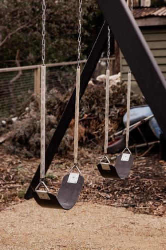 three swings with price signs on them on a playground at 'Sisters' - Cliff top cabin with hot tub in Spring Beach