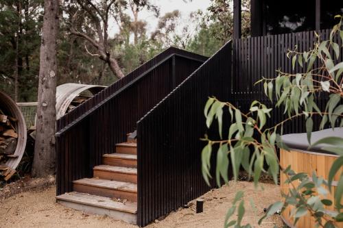 a black fence with a staircase in a yard at 'Sisters' - Cliff top cabin with hot tub in Spring Beach