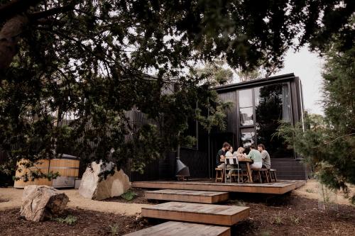 a group of people sitting at a table in front of a house at 'Sisters' - Cliff top cabin with hot tub in Spring Beach