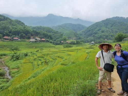 two people standing on a dirt road next to a field at Inh La Home Pu Luong in Pu Luong