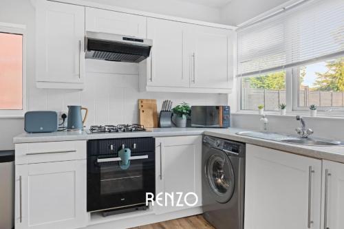 a kitchen with white cabinets and a washer and dryer at Vibrant and Cosy 3-Bed Home in Nottingham by Renzo, Perfect for Contractors, Free Parking! in Beeston