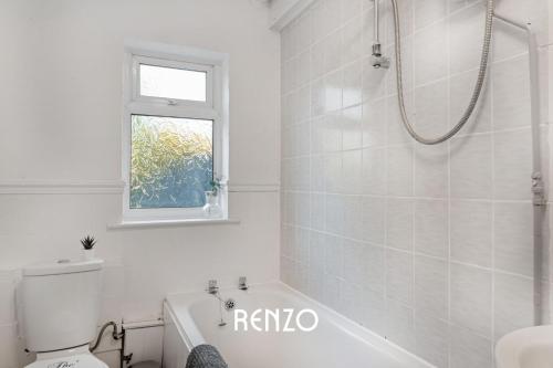 a white bathroom with a shower and a toilet at Vibrant and Cosy 3-Bed Home in Nottingham by Renzo, Perfect for Contractors, Free Parking! in Beeston