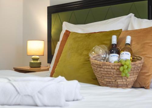 マコーにあるHagyma Panzióのベッドの上にワインボトルとブドウのバスケットを用意しています。