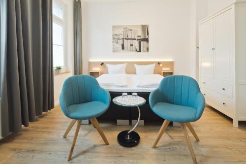 duas cadeiras e uma mesa num quarto com uma cama em Haus Menno Janssen - Doppelzimmer em Norderney