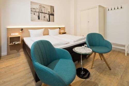 a hotel room with a bed and two chairs at Haus Menno Janssen - Doppelzimmer in Norderney