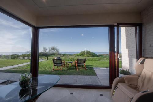 a living room with a table and chairs and a large window at Amber VIP Hotel in Pāvilosta
