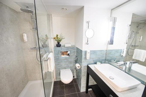 a bathroom with a sink and a toilet and a shower at Holiday Inn Lübeck by IHG in Lübeck