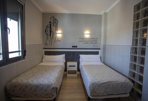 a room with two beds in a room with a window at Hotel LB Villa De Cuenca in Cuenca
