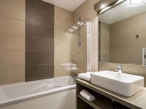 a bathroom with a sink and a tub and a mirror at appartement pont du Gard, Remoulins in Remoulins