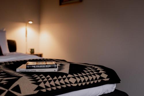 a stack of books sitting on top of a bed at 'Sisters' - Cliff top cabin with hot tub in Spring Beach