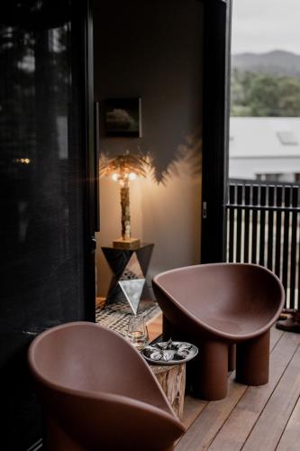 two chairs on a deck with a table and a lamp at 'Sisters' - Cliff top cabin with hot tub in Spring Beach