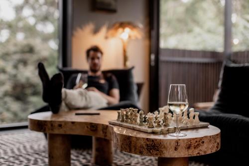 a man is sitting in a chair with a glass of wine at 'Sisters' - Cliff top cabin with hot tub in Spring Beach
