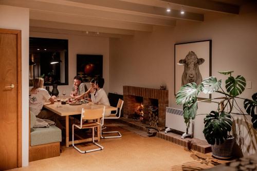 a group of people sitting at a table in a living room with a fireplace at 'Sisters' - Cliff top cabin with hot tub in Spring Beach