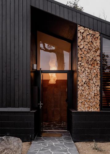 a building with a door and a pile of logs at 'Sisters' - Cliff top cabin with hot tub in Spring Beach