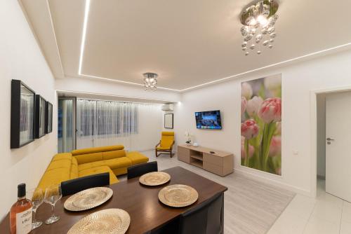Smile Apartments في بوخارست: غرفة معيشة مع أريكة صفراء وطاولة