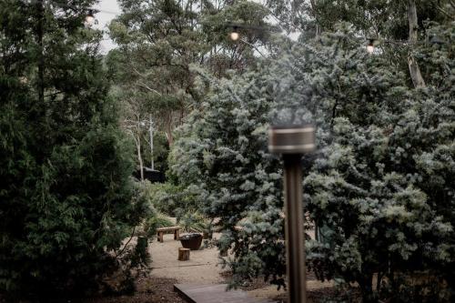 a pole with smoke coming out of it next to trees at 'Sisters' - Cliff top cabin with hot tub in Spring Beach