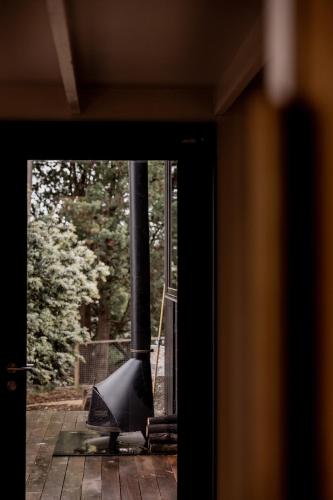 an open door with a stove in a house at 'Sisters' - Cliff top cabin with hot tub in Spring Beach
