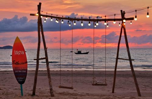 a surfboard on the beach with a boat in the ocean at iSea by the sea in Ninh Van Bay