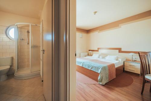 a bedroom with a bed and a bathroom with a shower at Villa Dorottya in Balatonföldvár